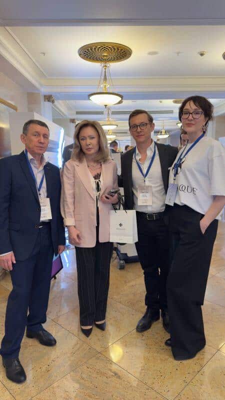 Четыре человека в деловой одежде с бейджами в конференц-зале.